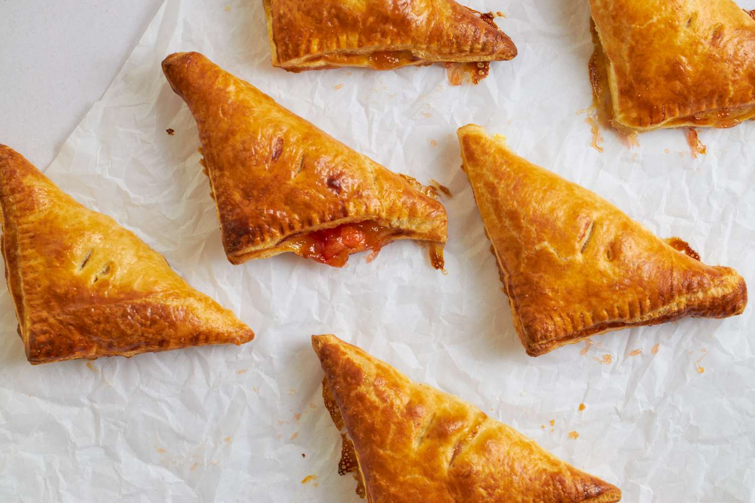 Peach turnovers on parchment paper partially filled with fruit filling