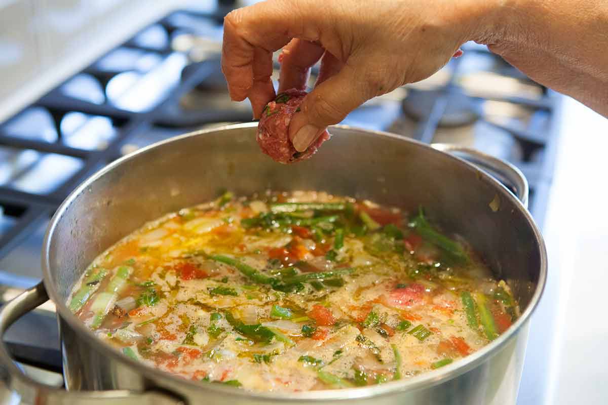 Meatballs being dropped in a albondigas soup to cook