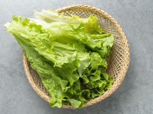 Romaine lettuce in a wicker basket arranged on a gray surface