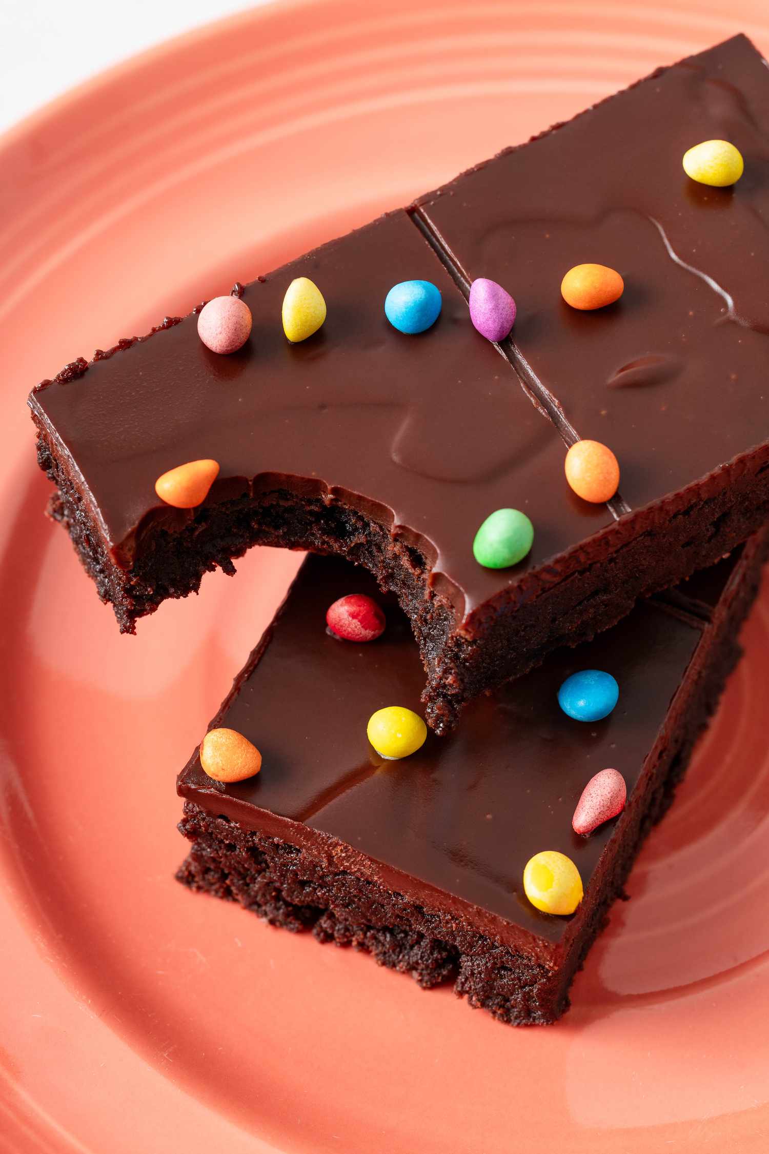 A stack of two homemade Cosmic Brownies on a plate with the top missing a bite 
