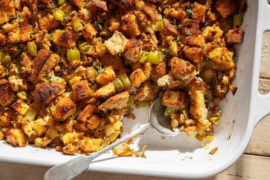 A dish of Thanksgiving apple sausage stuffing with a serving spoon placed inside