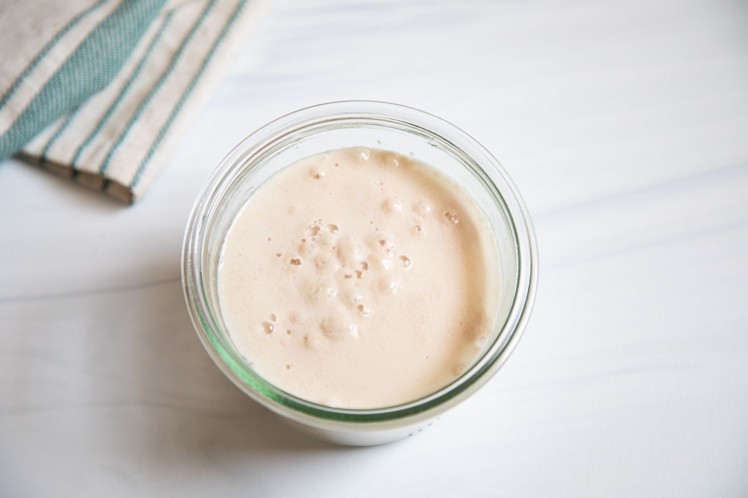 A glass cup of proofed yeast.
