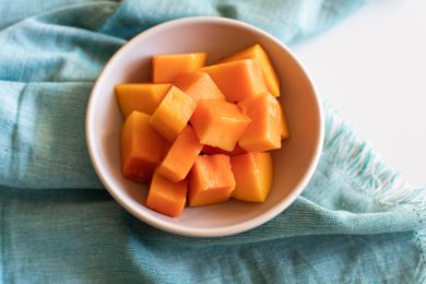 Papaya cubes in a white bowl on a blue napkin