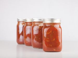 Four glass jars filled with tomato sauce arranged in a row