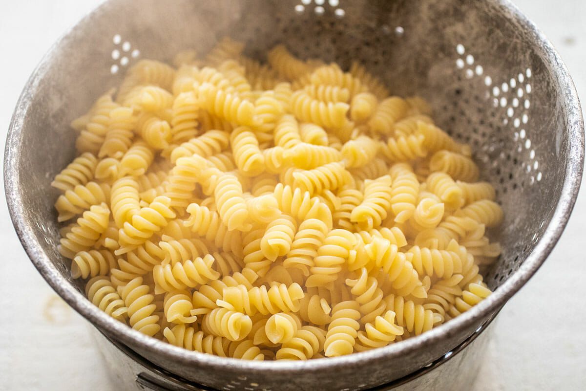Steaming cooked rotini pasta draining in a colander.