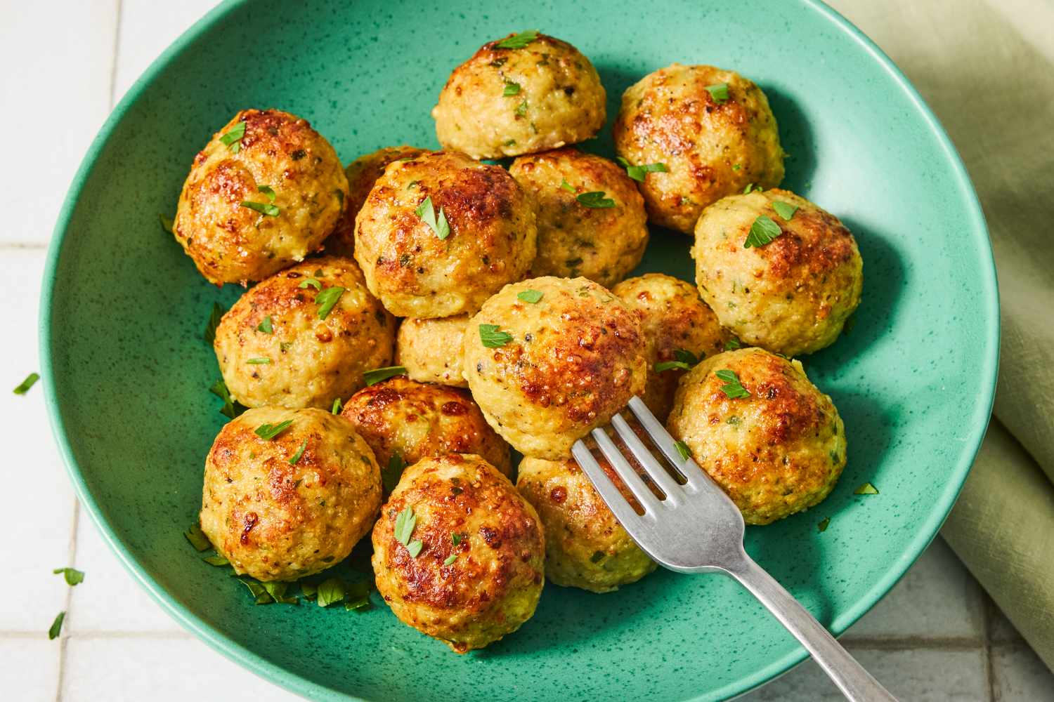 Chicken meatballs arranged on a plate with a fork placed on the side