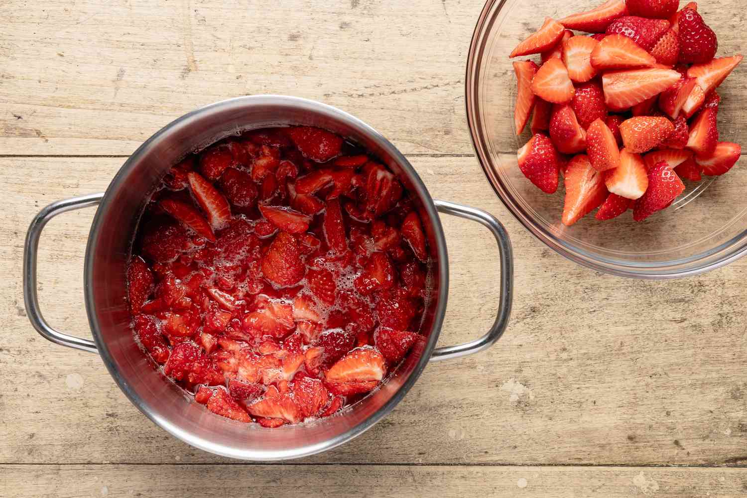 strawberries mashed in a bowl next to a bowl of strawberry slices for fresh strawberry pie recipe