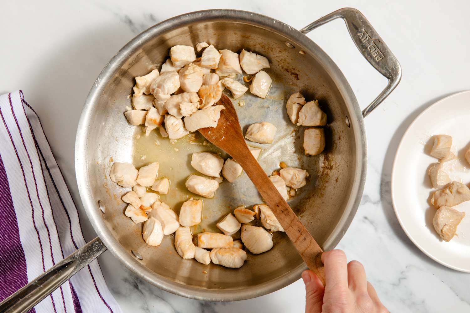 chunks of chicken cooking in a pan, hand stirring with wooden spoon for One-Pan Chicken Fajita Pasta
