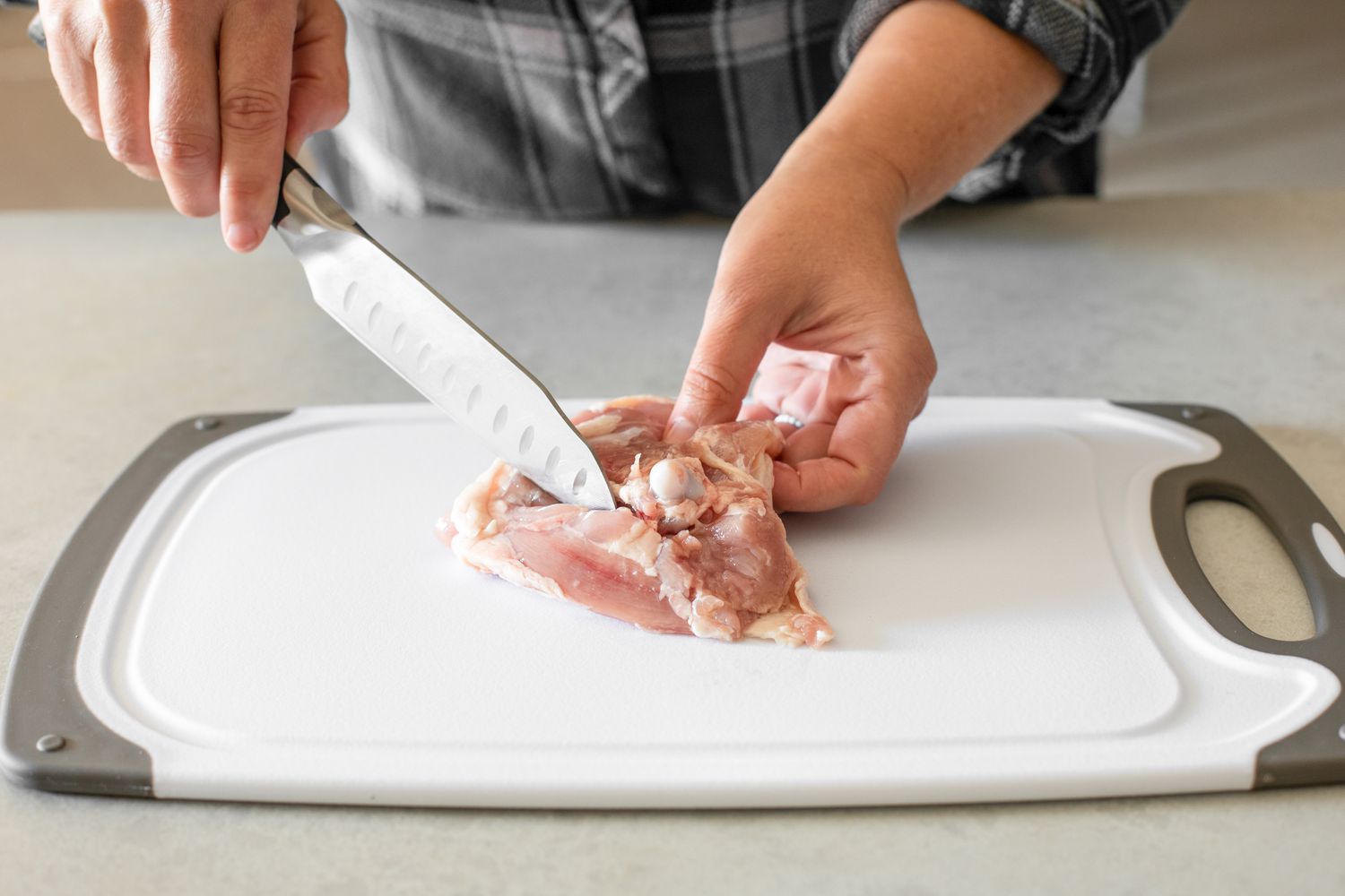 Knife Cutting Along the Bone While the Other Hand Holds the Chicken Thigh for Debone Chicken Thighs How-To
