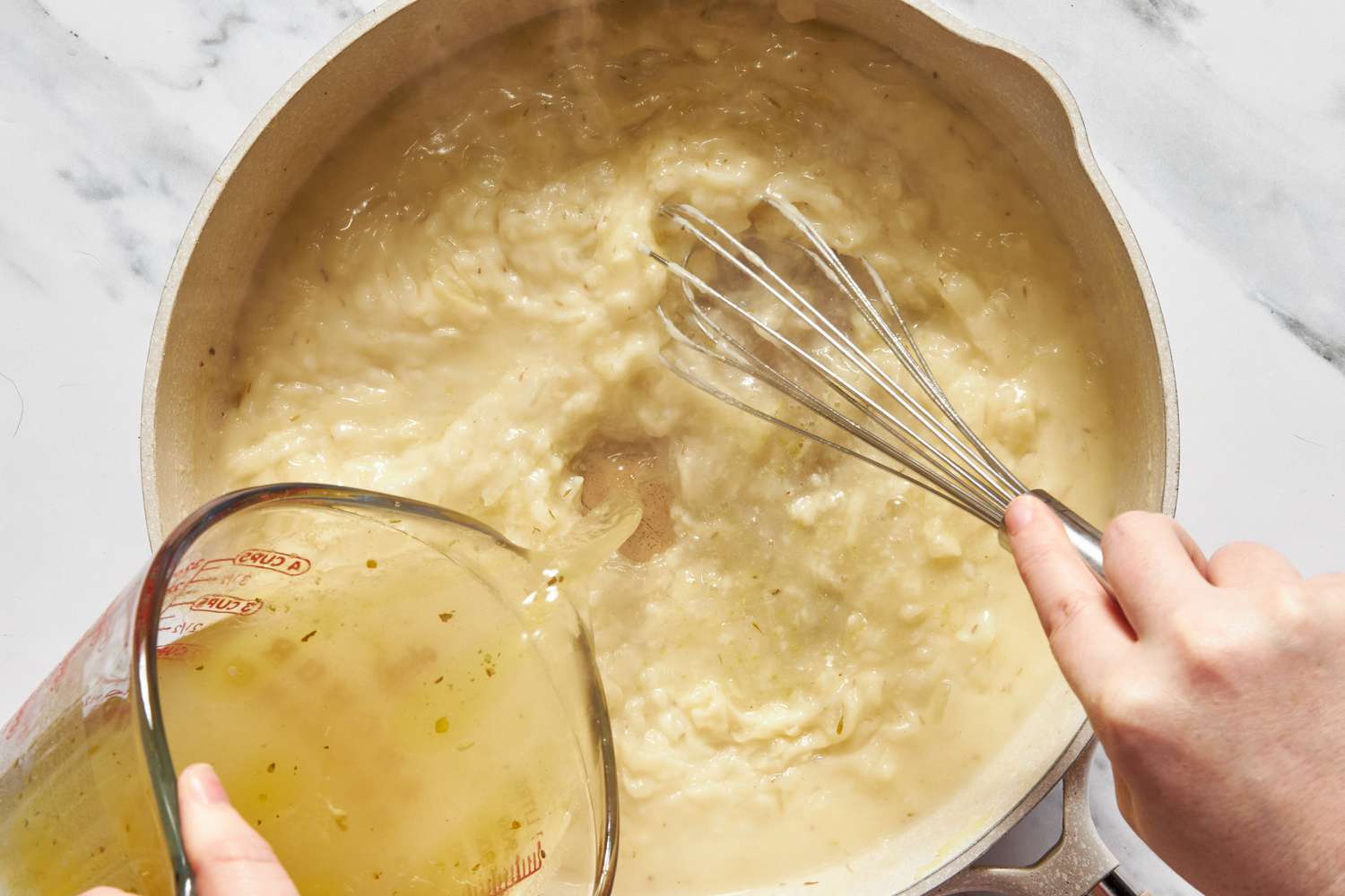 Broth whisked into the flour and onion roux in the pot for for chicken cobbler recipe with cheddar bay biscuit top