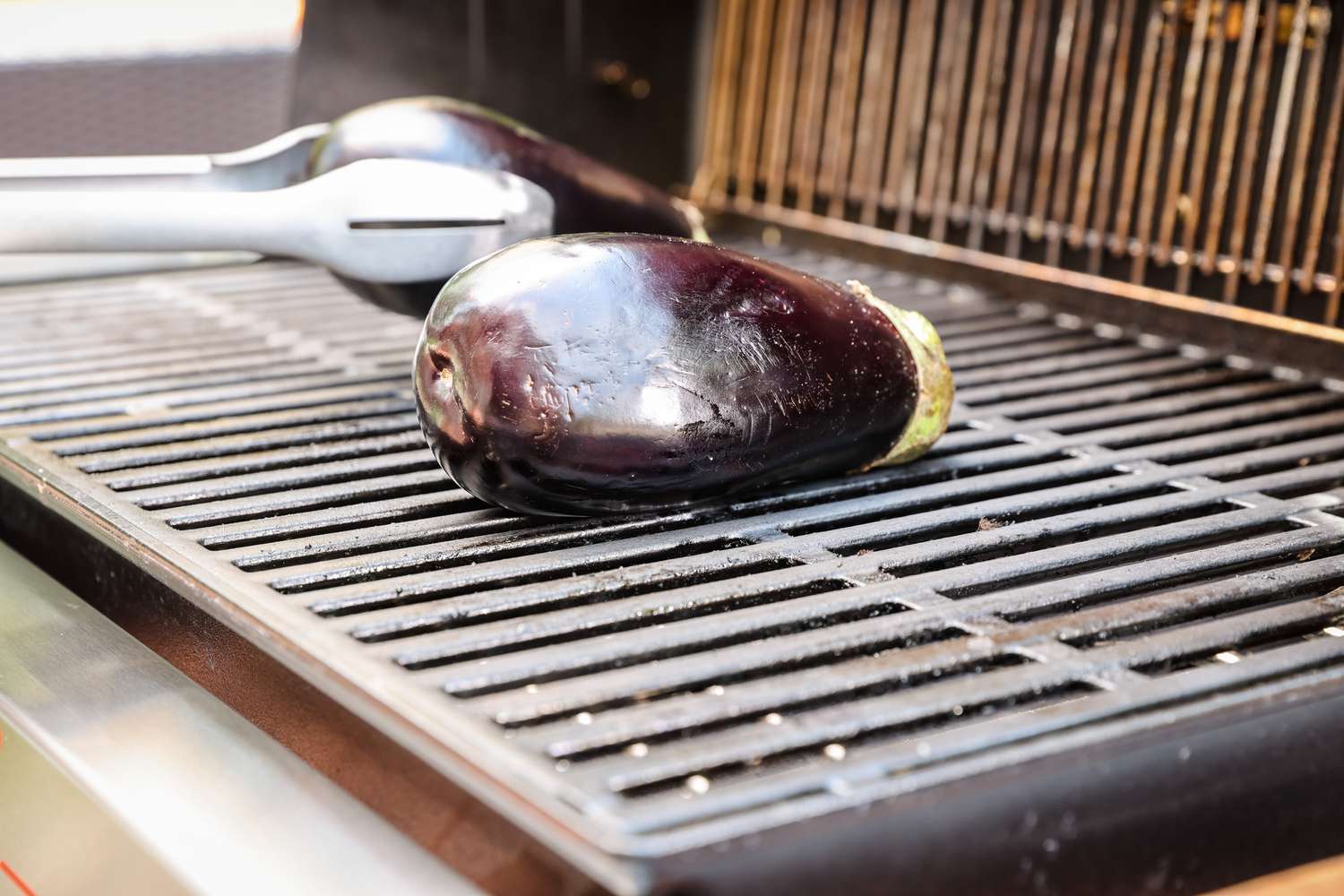 Whole Eggplant Placed on Grill with Tongs