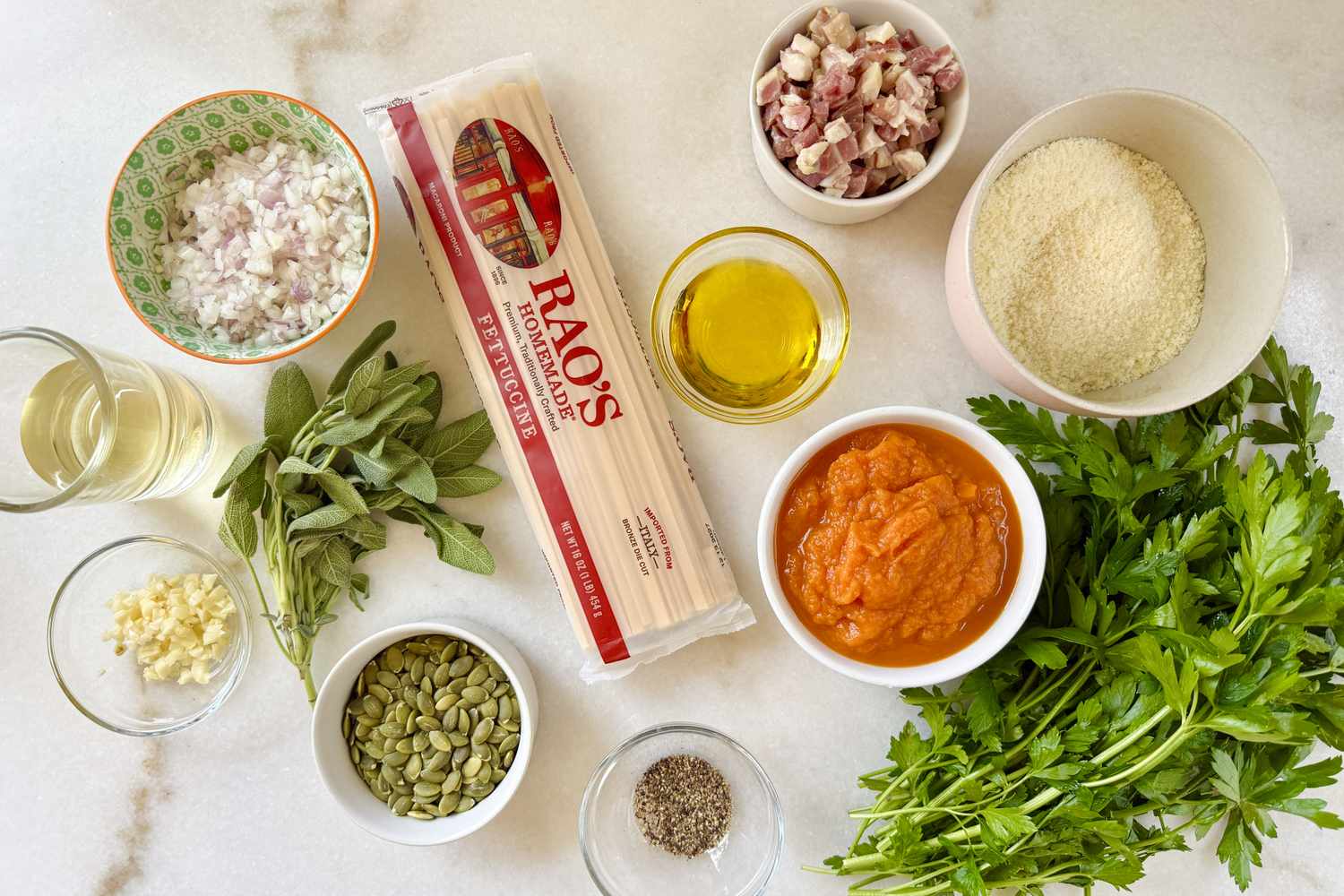 Ingredients for a pumpkin sage pasta dish arranged on a surface including pasta pumpkin puree sage parmesan pancetta and oil