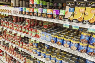 Grocery store shelves stocked with various brands of canned soups and broths