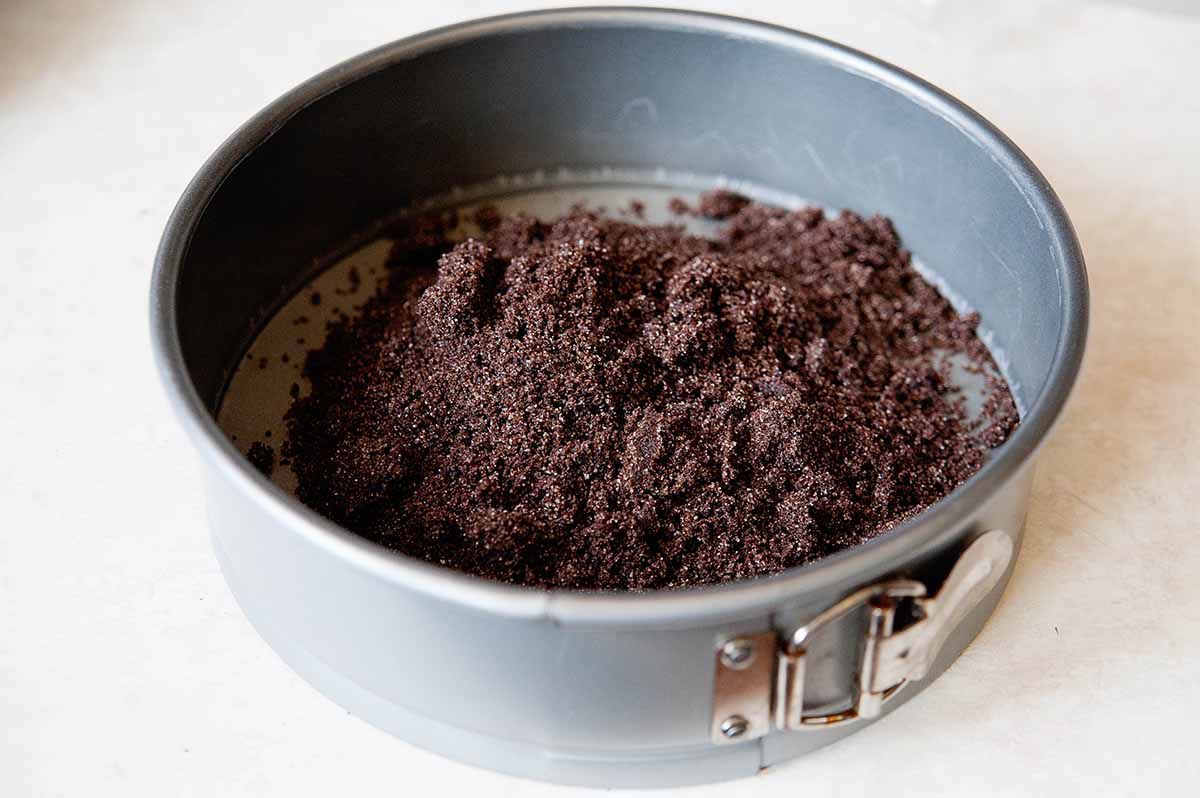 Chocolate graham crackers ground up and dumped into a spring form pan to make the crust for a homemade chocolate cheesecake.
