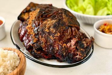 Plate of roasted meat with side accompaniments like rice and green lettuce