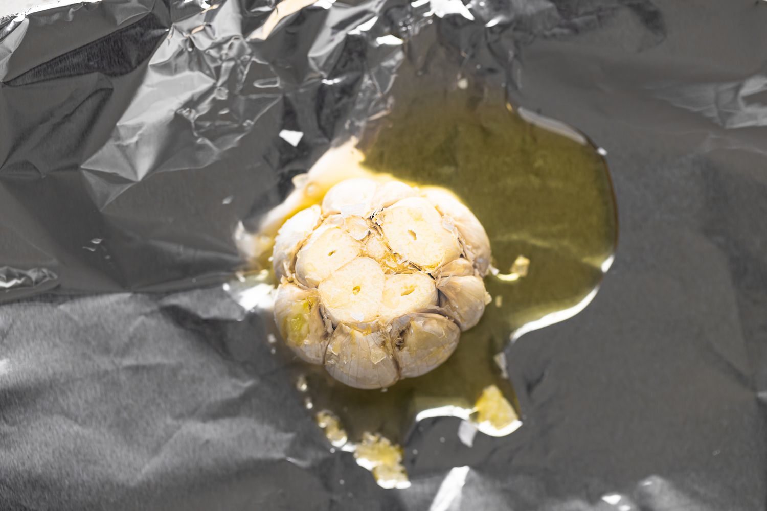 A head of garlic with olive oil on foil to make garlic mashed potatoes.