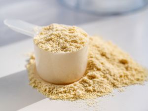 A scoop filled with protein powder with some powder spilled on a surface illustrating the ingredient