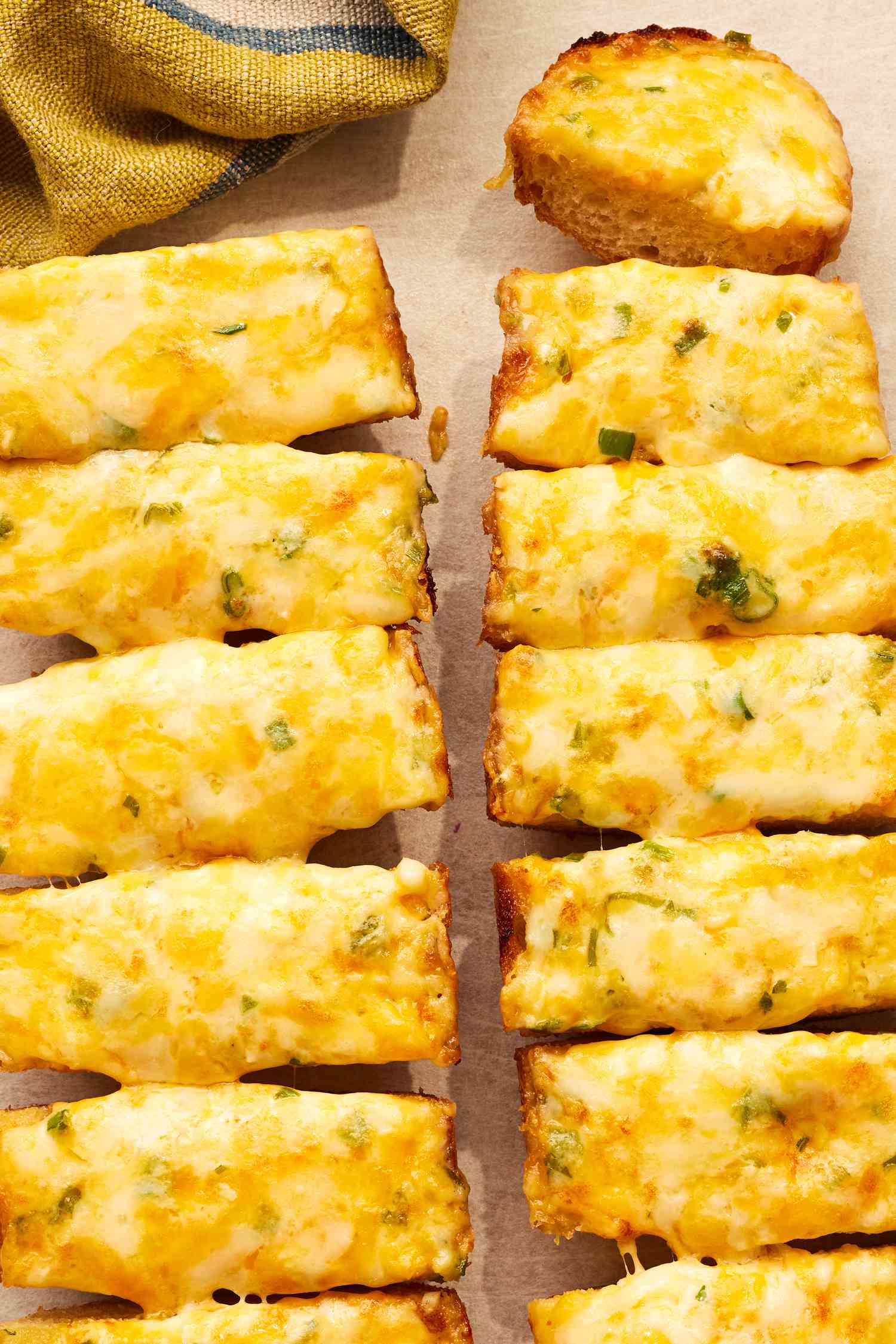 Cheesy Bread Cut Into Slices and a Yellow and Blue Colored Kitchen Towel