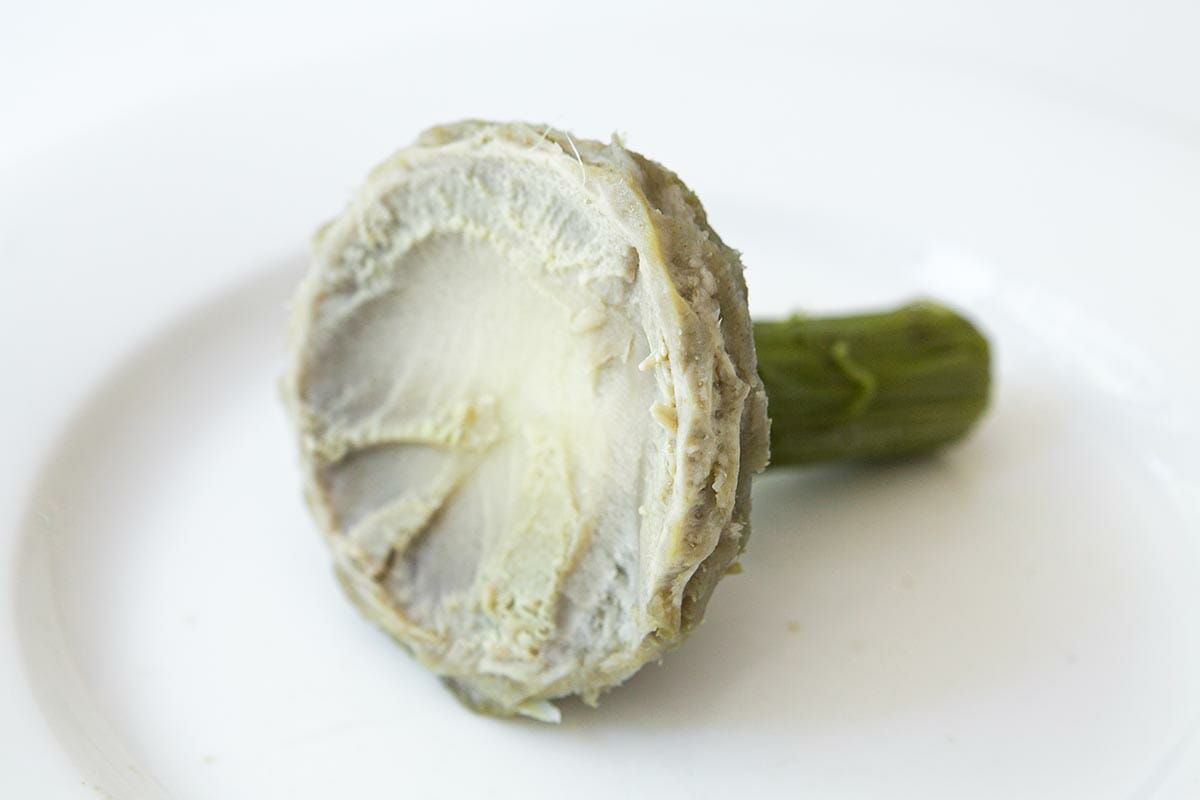A cooked artichoke heart on a plate, ready to eat