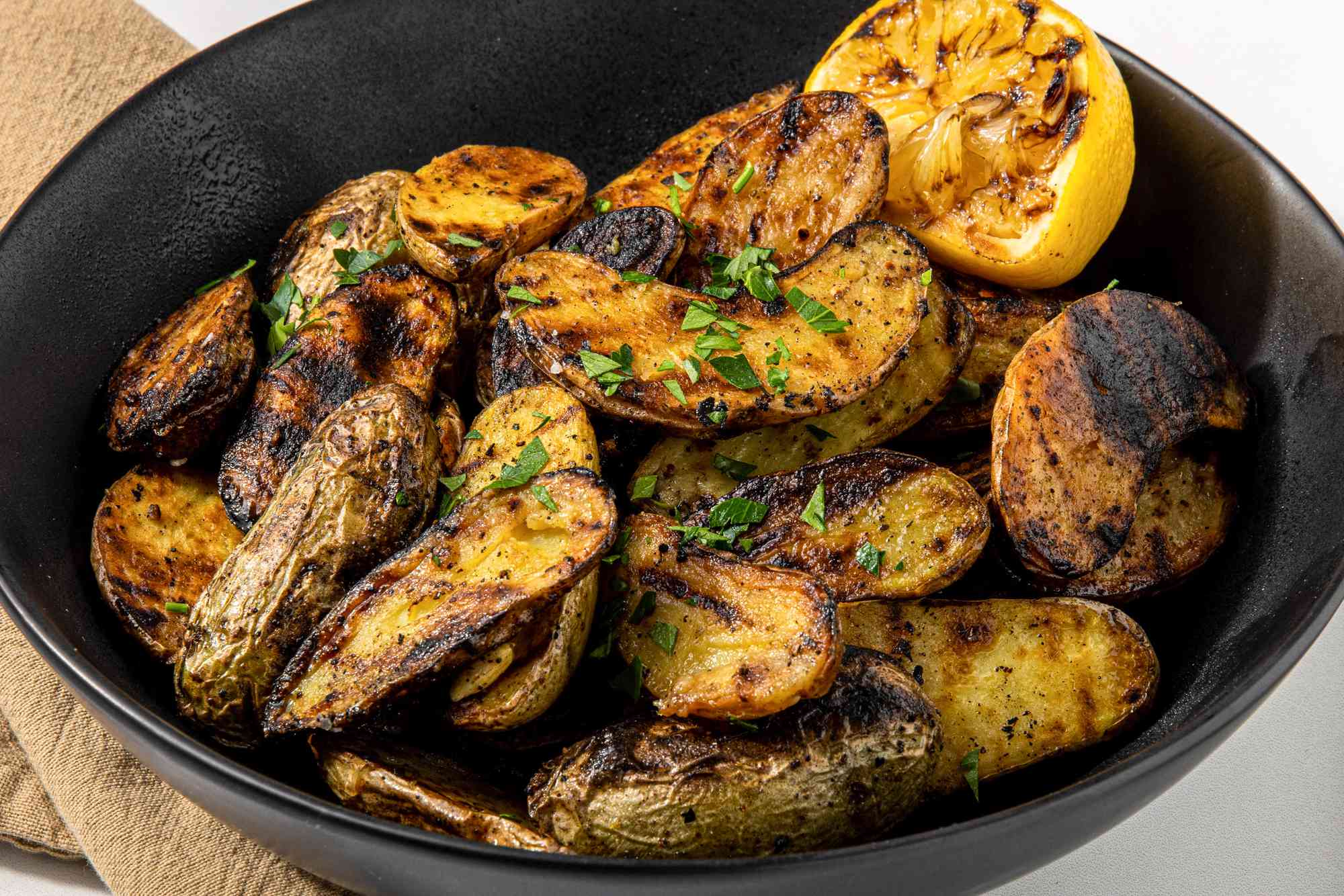 Grilled Fingerling Potatoes and a Grilled Halved Lemon in a Black Bowl 
