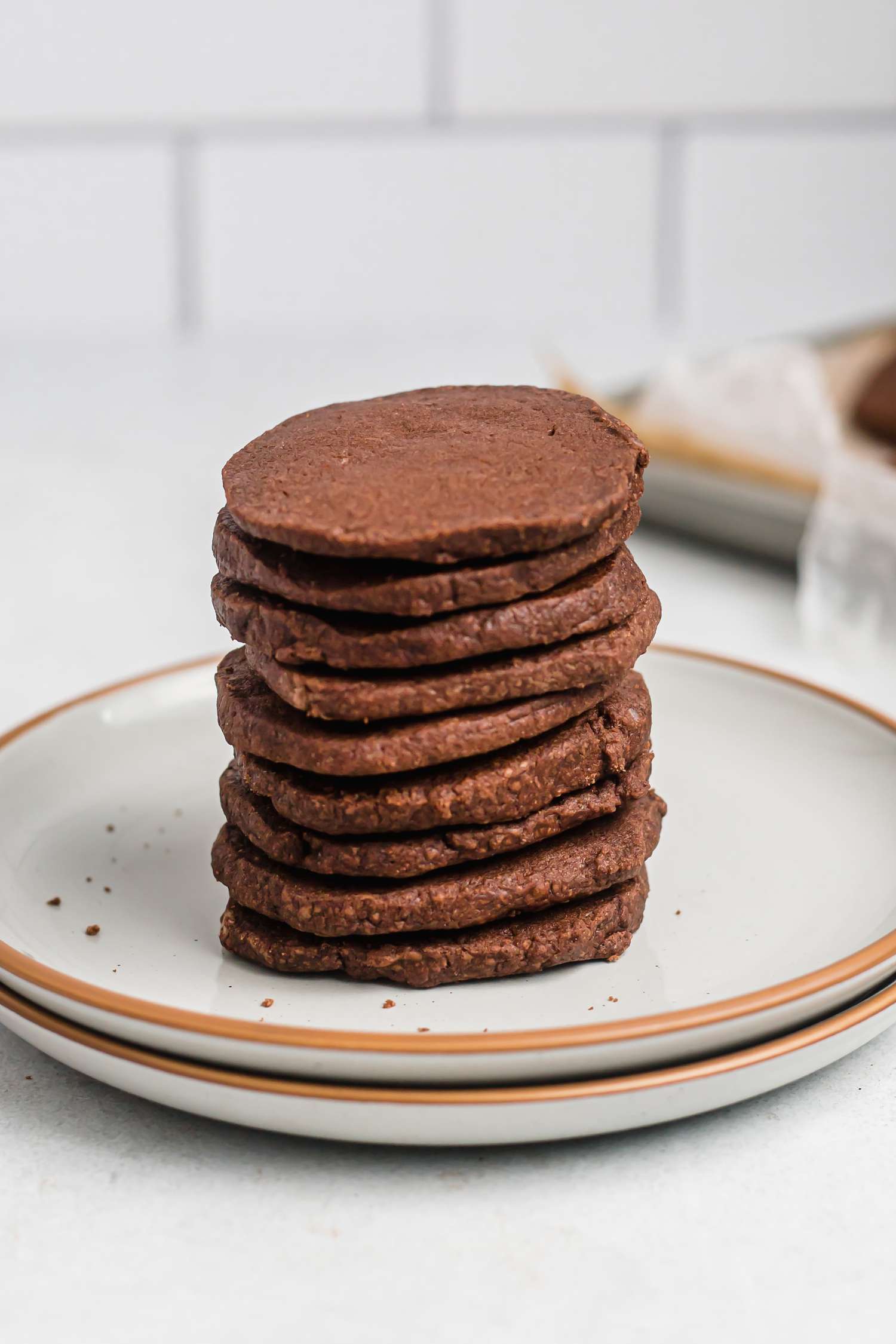 Tender chocolate butter cookies stacked on a ceramic plate.