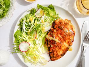 Chicken dinner on a plate with a side salad at a table setting