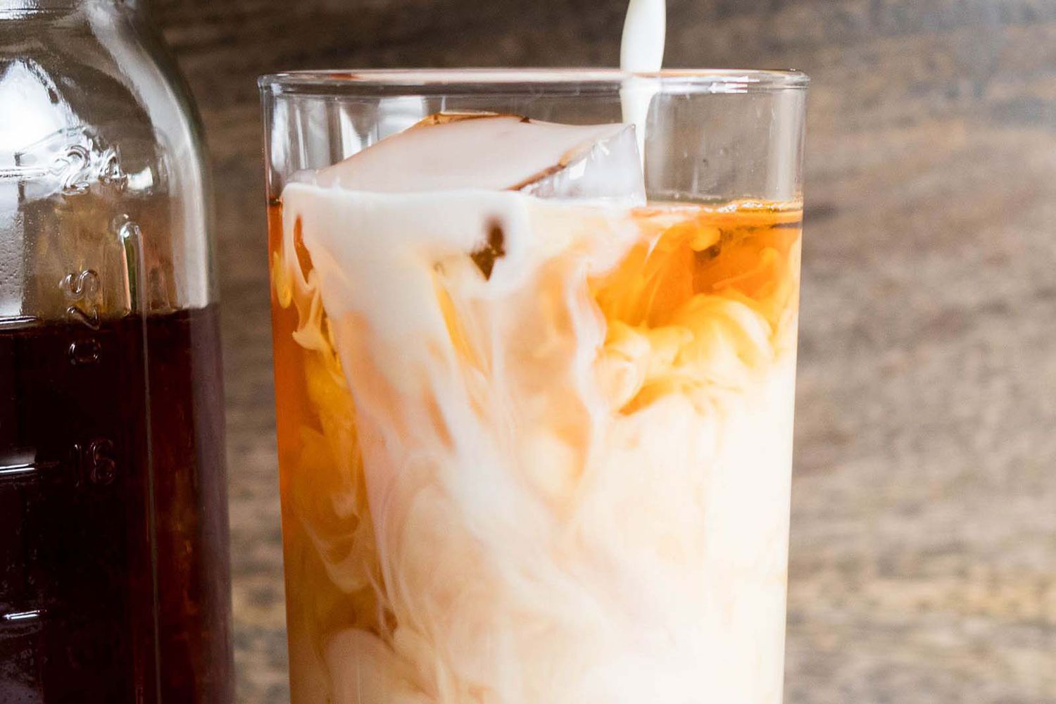 Milk being poured into a glass of iced chai