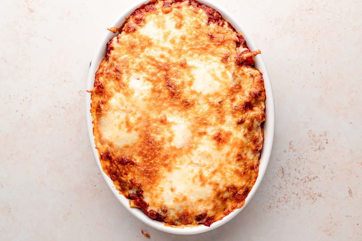 Baked ziti in an oval baking dish.