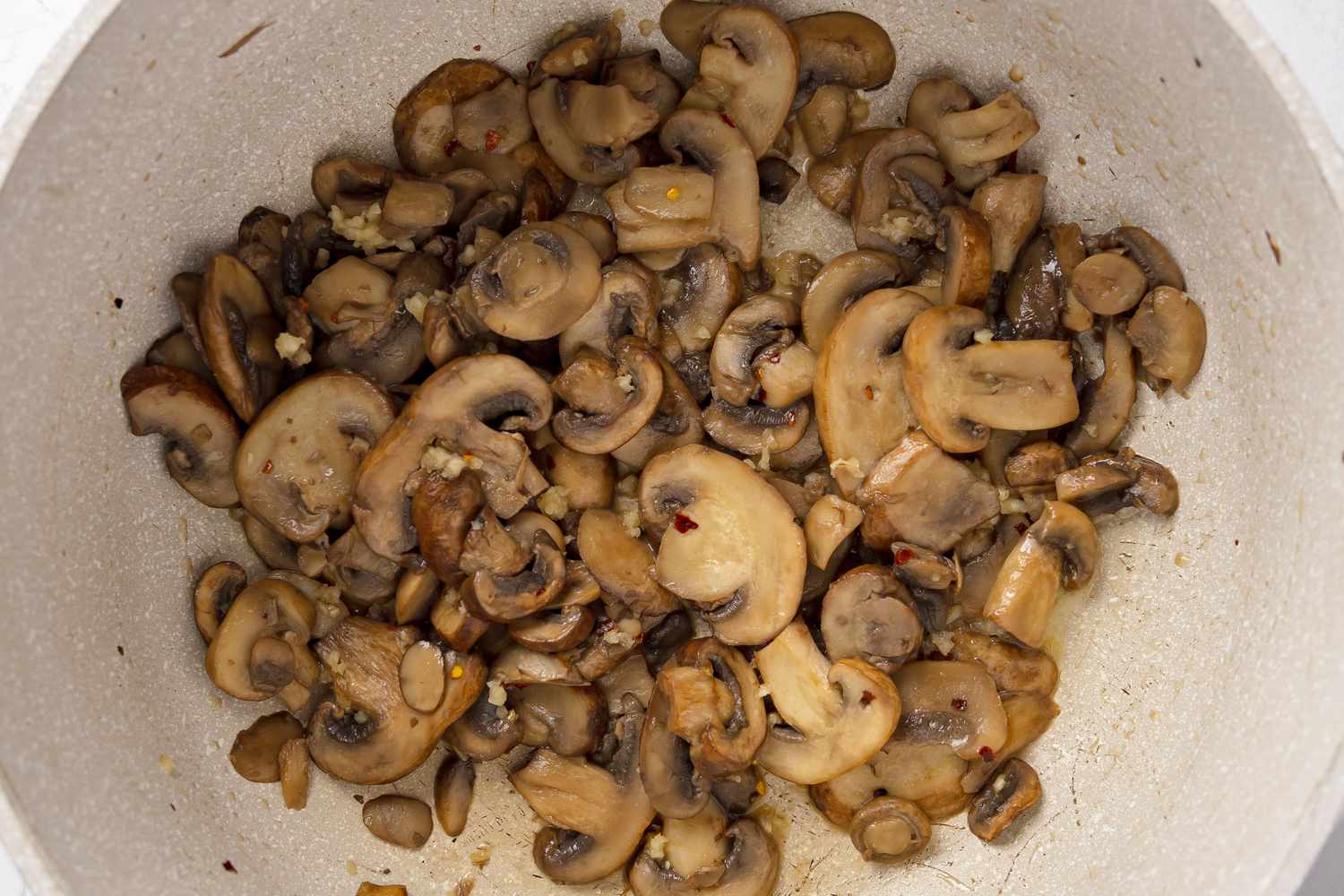 Seasoning and Garlic Added to Cooked Mushrooms for Green Bean Casserole in a Slow Cooker Recipe