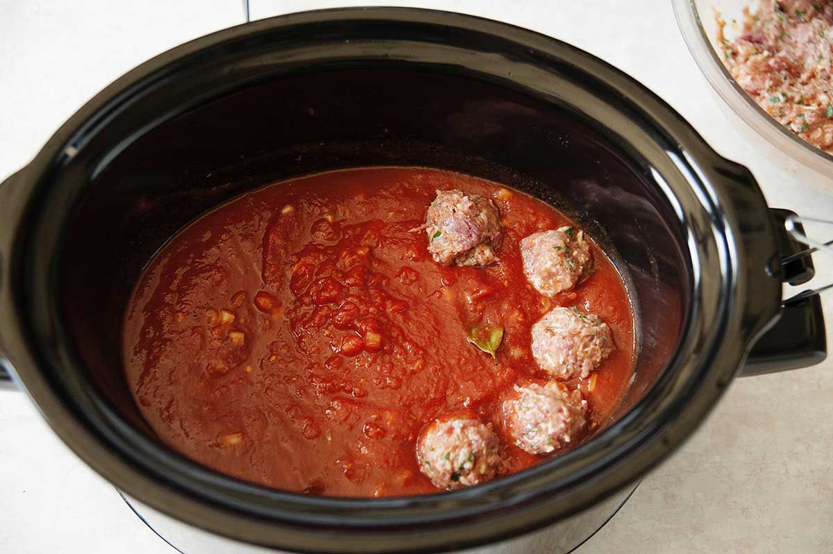 Meatballs in a slow cooker filled with tomato sauce.