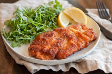 chicken schnitzel on plate with arugula and lemons