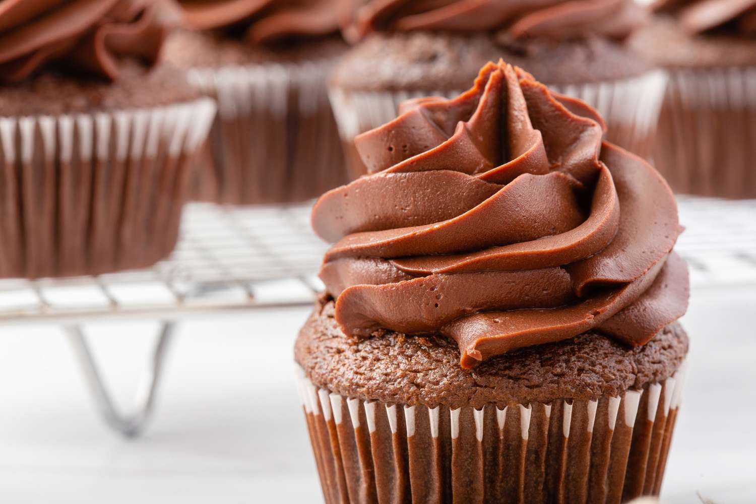 Side view of a chocolate cupcake with chocolate frosting swirled on top.