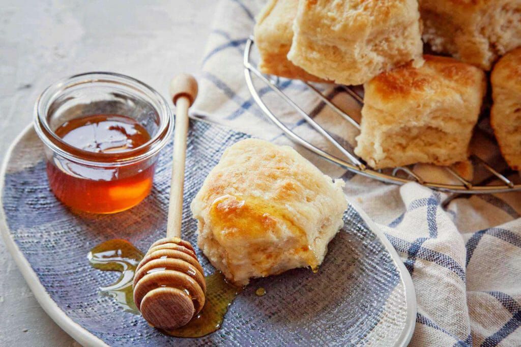 Angel biscuits served with honey on a blue plate