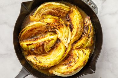 Cooked wedges of cabbage arranged in a skillet