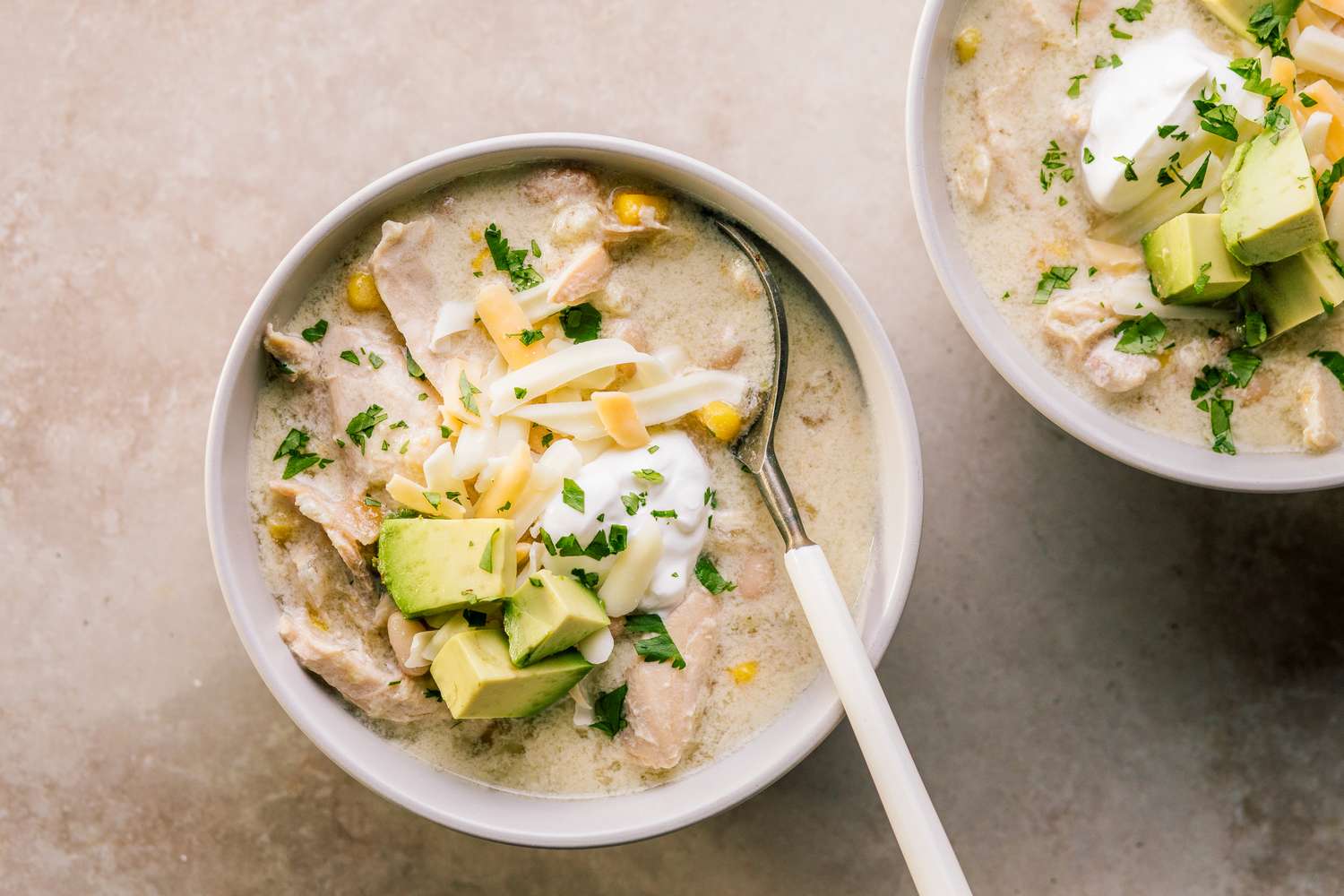 Bowls of chicken enchilada soup topped with avocado cheese and sour cream