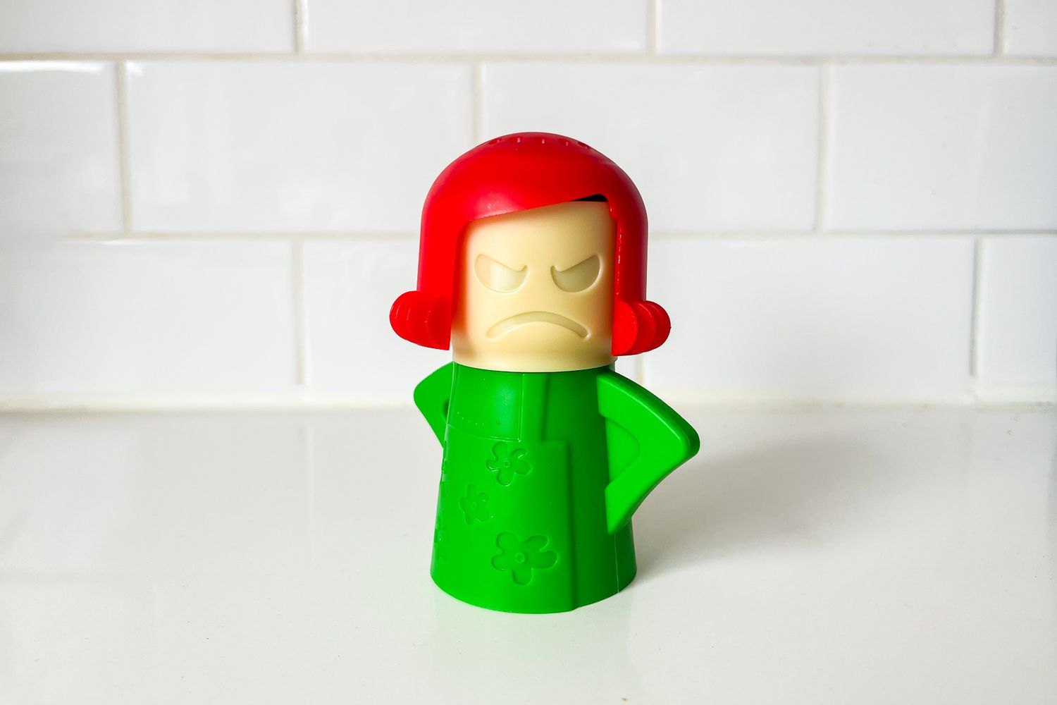 A kitchen cleaning tool in the shape of a figure with a red head and green body, designed to hold cleaning or deodorizing solutions