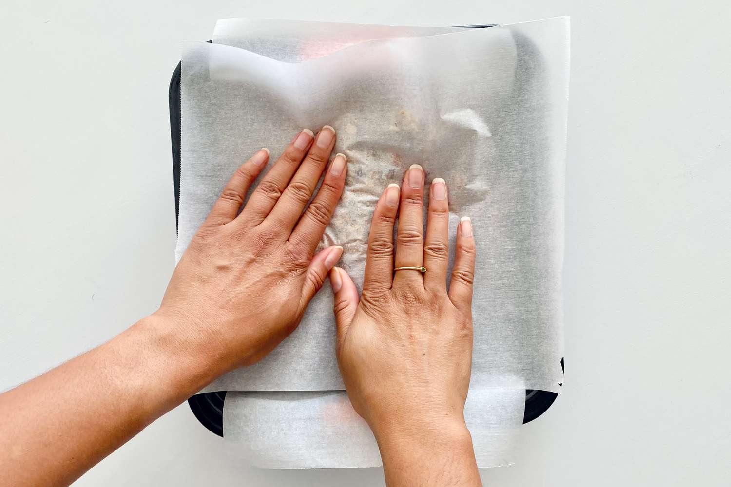 Pressing mixture flat with parchment paper to make Homemade Chewy Granola Bars.