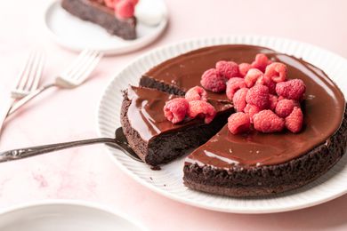A Slice of Flourless Chocolate Cake Garnished with Fresh Raspberries Lifted on a Pie Server