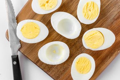 Hard boiled eggs sliced in horizontally and set on a wooden board.