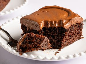 Angled view of a slice of Easy Brooklyn Blackout Cake on a white plate with a fork holding a bite removed from the slice