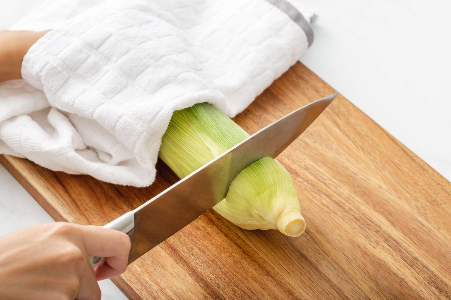 An ear of corn on a cutting board to show how to make corn on the cob.