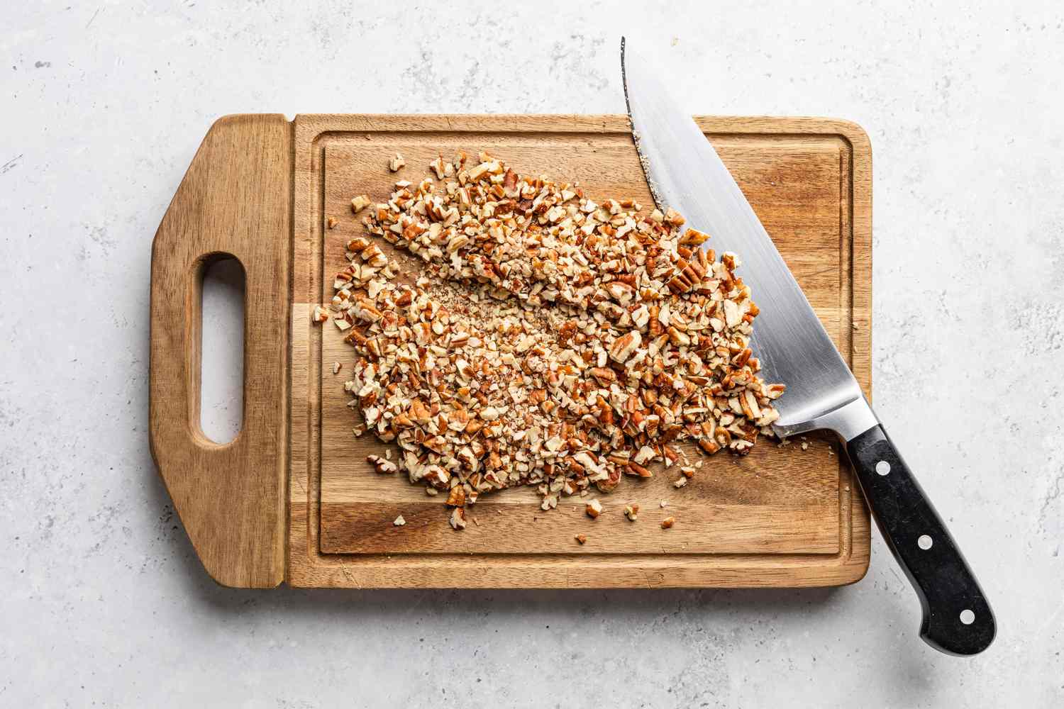 pecans cut into smaller pieces on a cutting board for soda cracker pie recipe