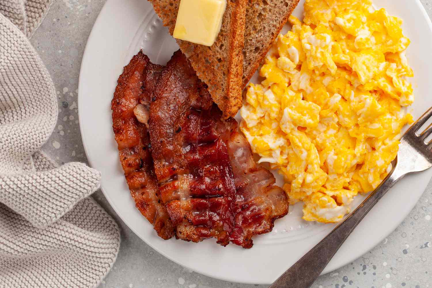 A traditional scrambled egg breakfast with crisp bacon and toast with butter