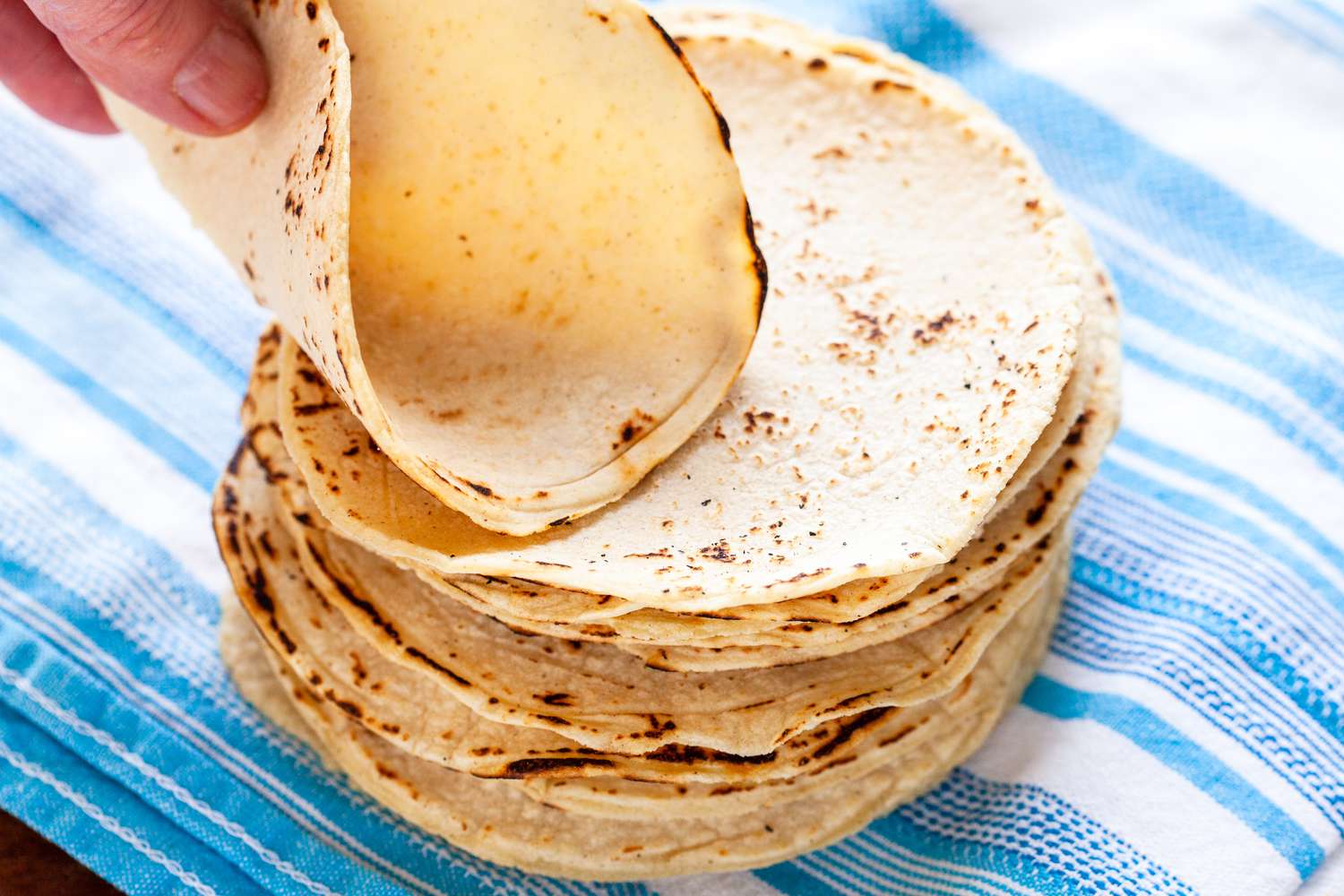Corn tortillas stacked on a blue striped linen napkin