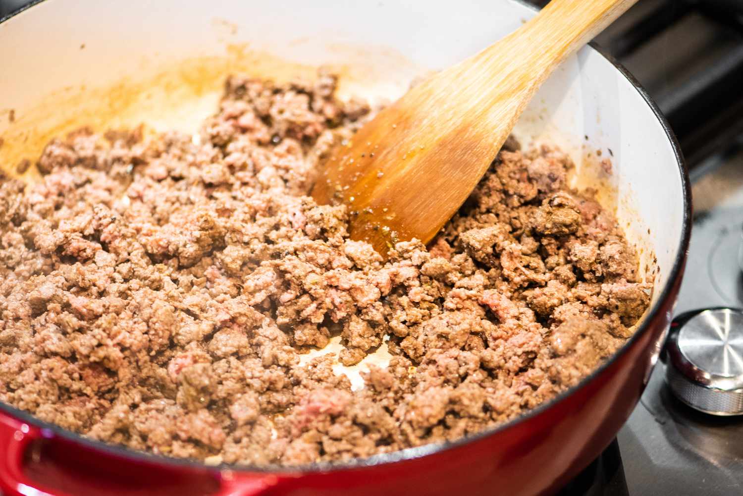 Wooden Spoon Stirring Ground Beef as It Cooks in a Dutch Oven for Homemade Hamburger Helper Casserole 