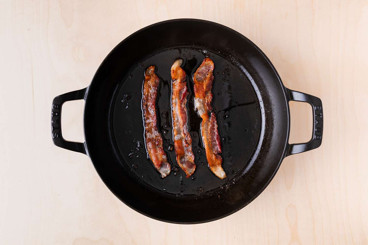 bacon cooking in a large cast iron skillet