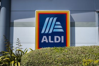Aldi store sign displayed on a building surrounded by some plants