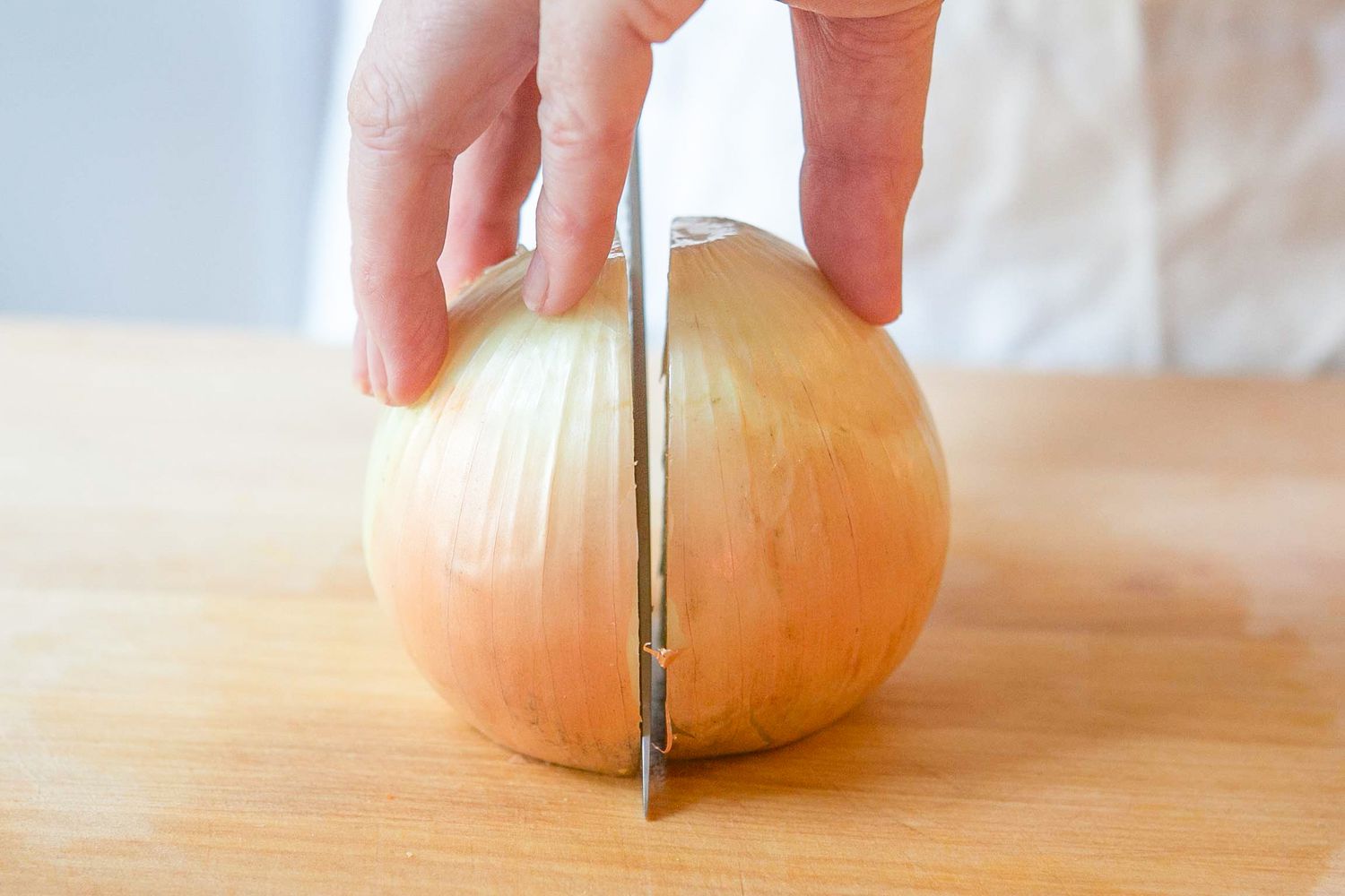 Onion Placed Cut Side Down on the Cutting Board, and the Knife Cuts the Onion in Half (from Top to Bottom) for How to Cut an Onion 