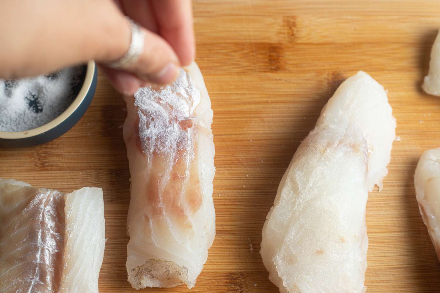 Seasoning fillets of cod to make fish poached in coconut with ginger and lime.