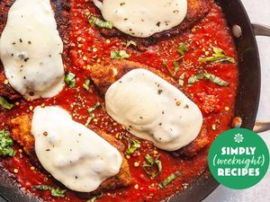 Chicken Parmesan with melted cheese in a skillet with tomato sauce and basil garnish